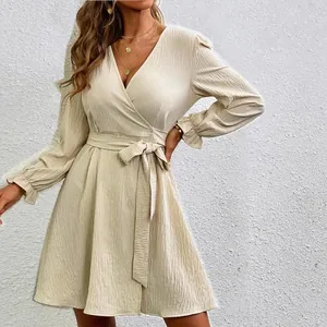 Close-up of elegant beige wrap dress with lantern sleeves and belted waist.