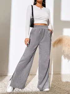 Detail view of women's gray high-waisted corduroy trousers with side slit hem design.