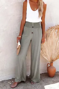 Close-up of the smocked high waist and button detail on green wide-leg linen pants.