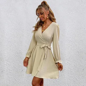 Detail view of a beige wrap V-neck dress with lantern sleeves and a tied waist belt.