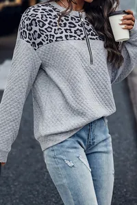 Detalle de sudadera acolchada gris para mujer con retazos de leopardo y media cremallera