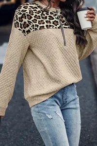 Detalle de sudadera acolchada para mujer con patchwork de leopardo y cremallera de un cuarto.