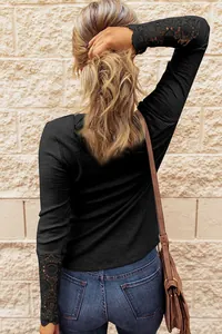 Back view of a casual black long-sleeved waffle knit top featuring elegant lace cuff details