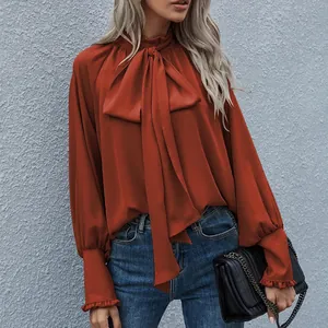 Detailansicht einer eleganten orangefarbenen Bluse mit Schluppe und Puffärmeln