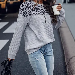 Sudadera casual acolchada con retales de leopardo y cremallera en un fondo de calle urbana