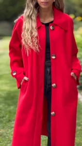 Detail view showing the vibrant red wool fabric and large decorative buttons of the coat
