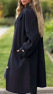 Detailed view of a navy blue long wool coat with elegant gold buttons and pocket.