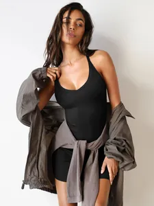 Close-up of a black ribbed bodycon camisole dress styled with a grey jacket in Y2K vibe