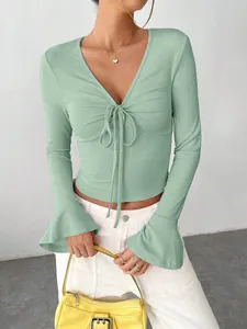 Close-up of a ribbed sage green V-neck top with stylish bell sleeves and front tie detail.