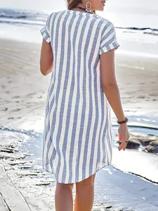Back view of a casual blue and white vertical striped summer shirt dress on a beach