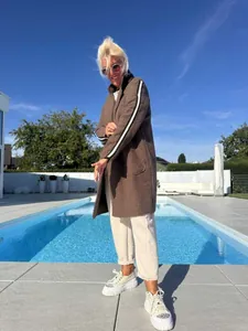 Elegante cardigan in pile di agnello marrone con strisce a contrasto indossato a bordo piscina