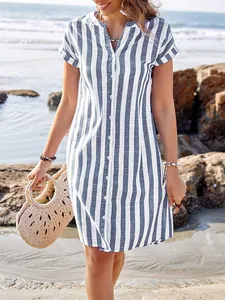 Close-up of a stylish blue and white striped summer shirt dress in a beach setting.