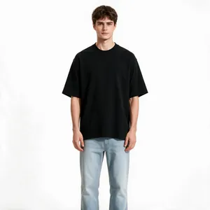 Full body view of a male model wearing a black oversized heavy cotton t-shirt with drop shoulders.