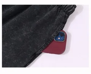 Close-up of acid-washed cotton shorts showing deep side pocket with a smartphone