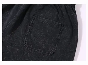 Close-up detail of vintage acid-washed black cotton shorts showing pocket and fabric texture