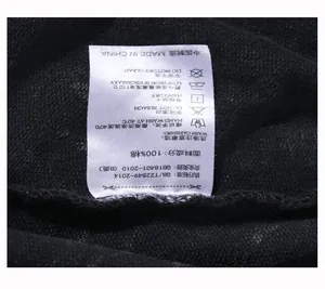 Close-up view of the white wash care label on black 100% cotton fabric garments