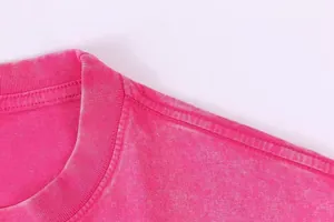 Primer plano detallado del cuello y la costura del hombro de una camiseta rosa vintage con lavado.