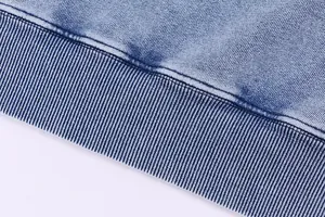 Macro detail view showing the ribbed hem texture of a vintage acid wash blue denim hoodie