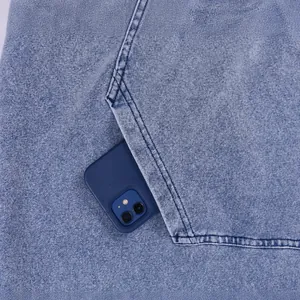 Detail of oversized acid wash denim hoodie featuring a large functional chest pocket.