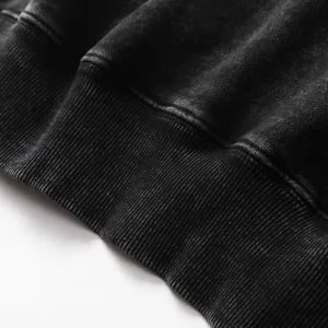 Close-up macro view of the ribbed hem on a heavy washed distressed oversized black hoodie