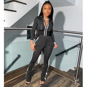 Black two-piece women's tracksuit with white side stripes and zip-up top detail.