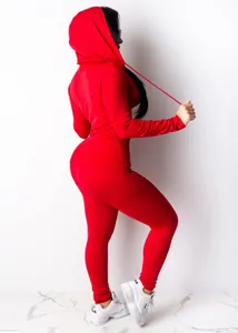 Back view of a woman in a red hooded two-piece sports set with slim fit leggings
