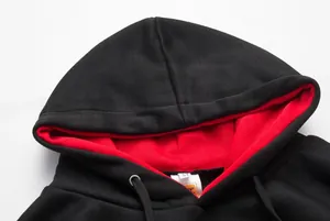 Close-up of black hooded sweatshirt featuring vibrant red inner hood lining