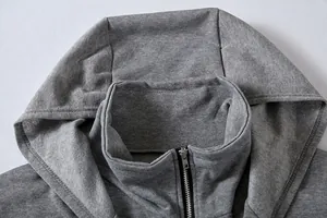 Detalle del cuello de una sudadera gris con capucha, cremallera y diseño de doble capa.