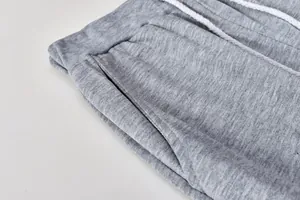 Primo piano di pantaloni della tuta grigi con vita elastica e coulisse bianca regolabile