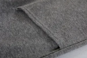 Detalle del tejido de punto gris y la costura de una chaqueta con capucha de mujer