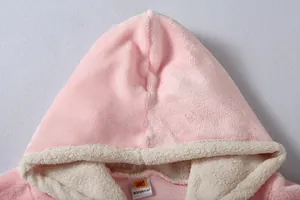 Detailed view of the pink plush oversized hoodie blanket featuring soft cream sherpa lining