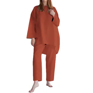 Dettaglio di set casual da donna color ruggine con maglia a maniche lunghe e pantaloni larghi.