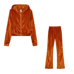 Two-piece orange velvet tracksuit set featuring a zip-up cropped hoodie and wide-leg pants.