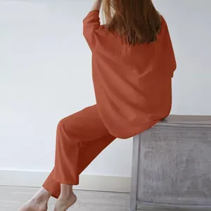 Vista posteriore di una donna che indossa un set lounge due pezzi arancione ruggine.