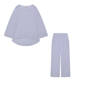 Completo minimalista bianco due pezzi con top largo a maniche lunghe e pantaloni ampi.