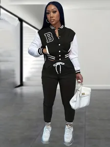 Vista completa di una giacca varsity bianca e nera e pantaloni jogger coordinati su un modello.