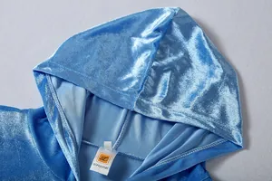 Close-up of light blue velvet hooded sweatshirt showing premium fabric texture and tag detail.