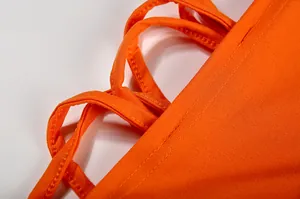 Gedetailleerde close-up van een oranje jurk met stiksels en veters om te strikken