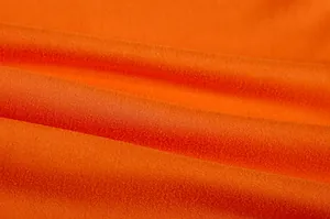 Close-up macro-opname van feloranje gebreide stoftextuur met fijne weefpatronen.