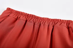 Dettaglio della vita elasticizzata su pantaloni casual arancione in tessuto