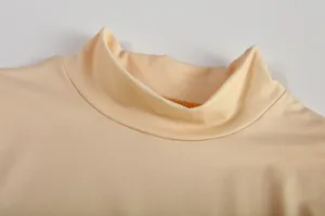 Gedetailleerde close-up van de zachte opstaande kraag en textuur van een abrikoosgekleurde top