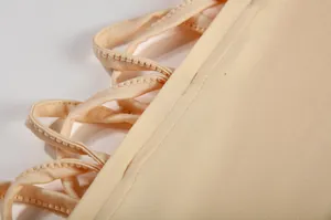 Gedetailleerde macro-opname van de vetersluiting en stiksels op een beige jurk