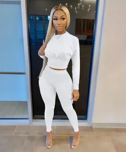 Model wearing a white long-sleeved crop top and matching leggings in a stylish pose.
