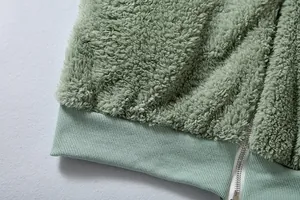 Detalle de cerca de la suave textura de vellón verde y cremallera plateada de la chaqueta