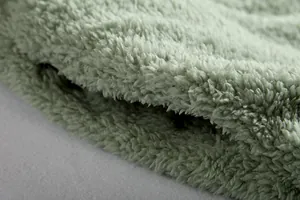 Primer plano detallado de la suave textura de la tela de felpa verde salvia de esta chaqueta