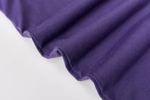 Detailansicht von weichem lilafarbenem Strickstoff mit glatter Textur und natürlichen Falten