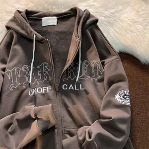 Detailansicht eines kaffeebraunen Oversized-Kapuzenpullis mit weißer Stickerei.