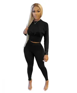 Full body view of a stylish black two-piece sporty outfit featuring a waist-slimming crop top