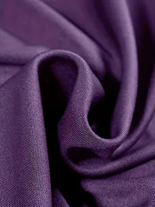 Dettaglio ravvicinato di tessuto viola strutturato con trama a maglia fine e pieghe morbide