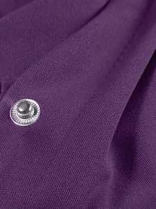 Primo piano della trama del tessuto della giacca da baseball viola con bottone argento.
